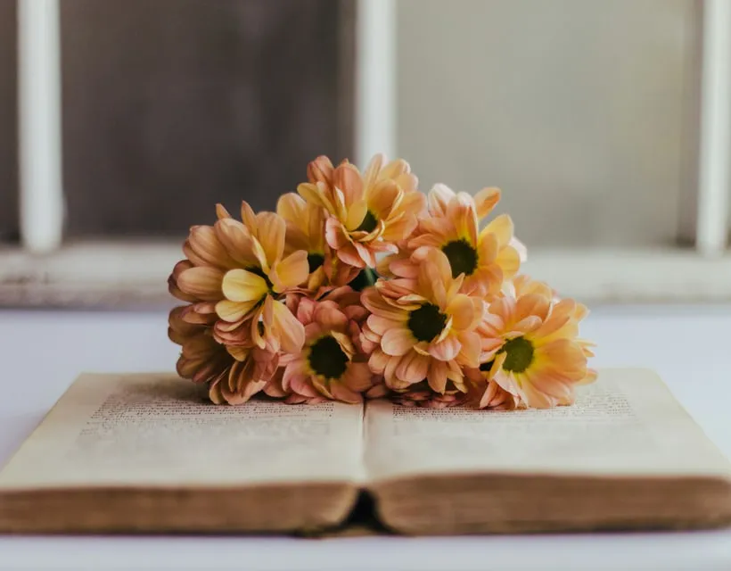 An open book resting beside flowers